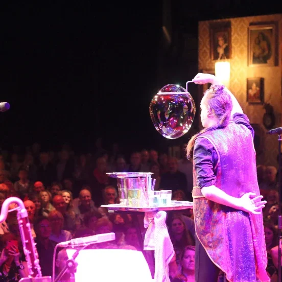 Zeepbellenkunstenaar Stephan Masur tijdens zeepbellenshow op evenement Zeepbelartiest met zeepbellen voor een publiek op een podium.