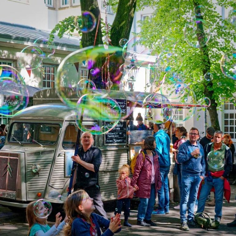 Straattheater met gigantische bellenblazers Bellenblaas artiest in actie met reuze zeepbellen walk-act – bubble show buiten in Vlaanderen