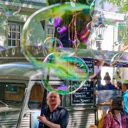 Zeepbellen zeepbellenstraatact in openluchtlocatie tijdens evenement Een persoon staat voor een kraampje en maakt enorme zeepbellen.