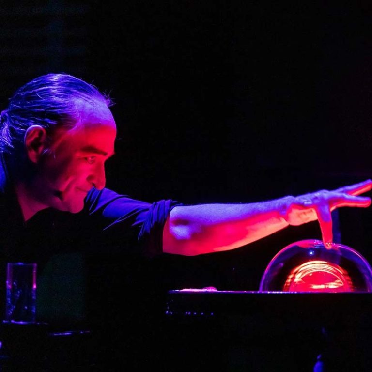 Zeepbellenkunstenaar op exclusief evenement in Nederland Een man interacteert met een gloeiende zeepbel op een tafel.